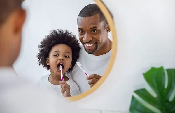 dad showing his son how to brush his teeth