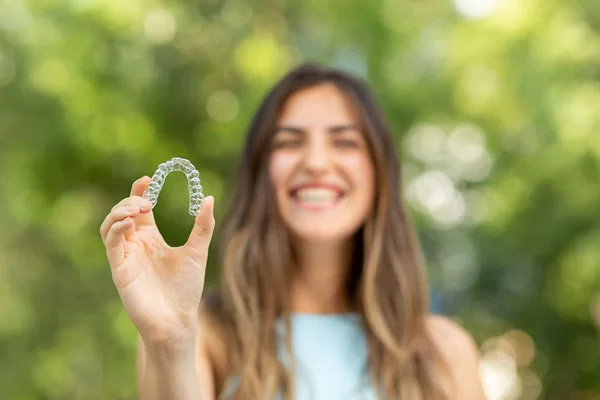 young lady holding a clear aligner