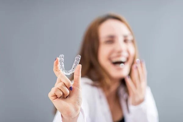 young woman holding a Invisalign clear aligner
