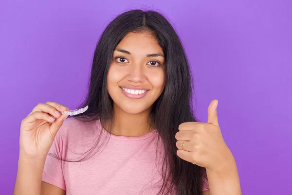 teen holding an Invisalign clear aligner tray