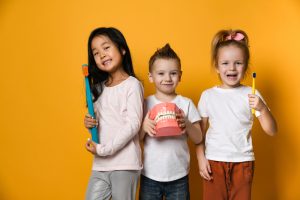 three kids holding models of dental related